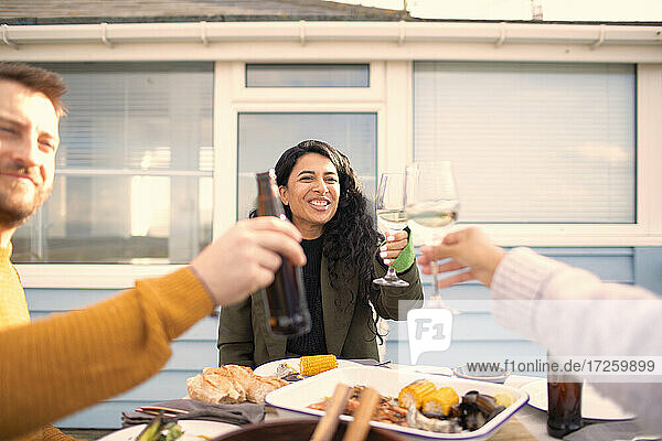 Glückliche Freunde stoßen bei Wein und Bier auf der Terrasse mit Meeresfrüchten an