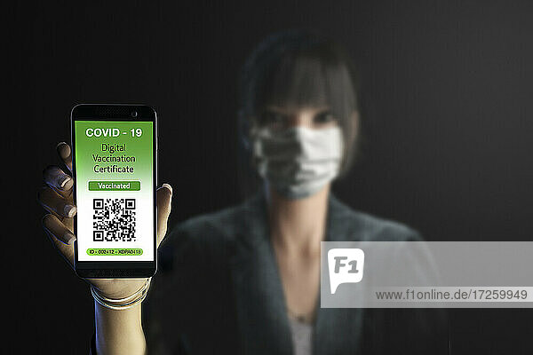 Porträt Geschäftsfrau in Maske mit digitalem Covid-Impfpass