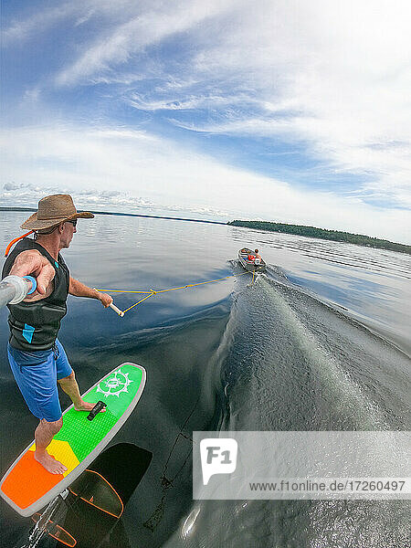 Der Fotograf Skip Brown fährt mit seinem Tragflügelboot hinter einem kleinen Boot auf dem Sebago Lake  Maine  Vereinigte Staaten von Amerika  Nordamerika