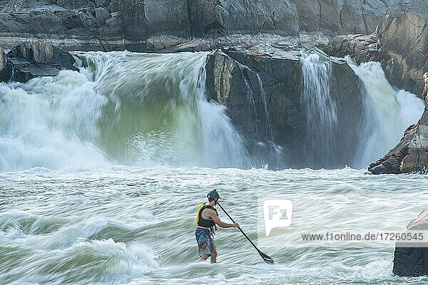 Ian Brown stand up paddle surfs challenging whitewater below Great Falls of the Potomac River  border of Maryland and Virginia  United States of America  North America