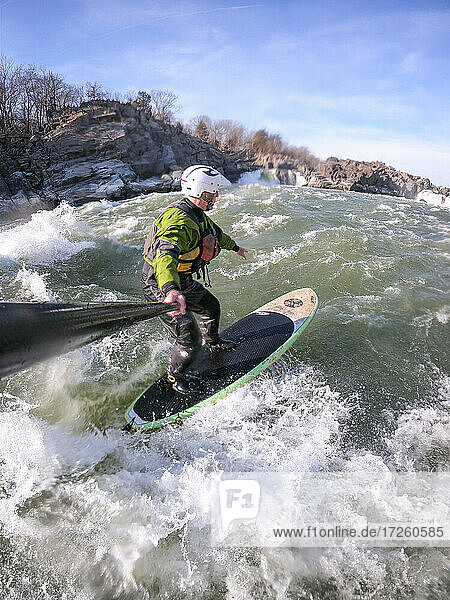 Photographer Skip Brown stand up paddle surfs in winter challenging whitewater below Great Falls of the Potomac River  border of Virginia and Maryland  United States of America  North America