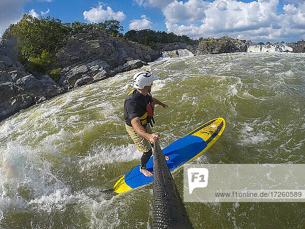Skip Brown surft mit seinem Stand Up Paddleboard im schnell fließenden Wildwasser auf dem Potomac River in der Nähe von Great Falls  Virginia  Vereinigte Staaten von Amerika  Nordamerika