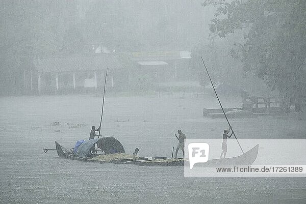 Collecting sand on a boat in the Pamba River during a rainy; monsoon day  Kerala
