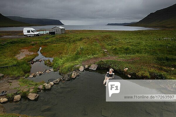 Natural pool at fjord  hot pot  geothermal spring  woman bathing Reykjafjarðarlaug  Vestfirðir  Westfjords  Iceland  Europe