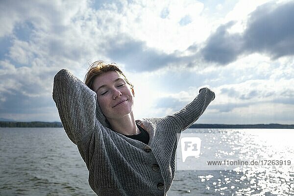 Young woman stretching happily  on the lake  Starnberger See  Upper Bavaria  Bavaria  Germany  Europe