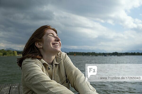 Young woman stretching happily  on the lake  Starnberger See  Upper Bavaria  Bavaria  Germany  Europe