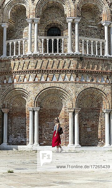 Young woman in red dress standing in front of Basilica dei Santi Maria e Donato  Murano  Murano Island  Venice  Veneto  Italy  Europe