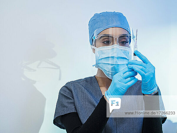 Krankenschwester mit Gesichtsmaske und Schutzschild bereitet Covid-19-Impfung vor