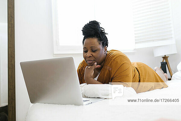 Frau arbeitet am Laptop im Bett