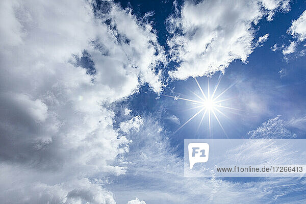 Sonnenfackel in blauem Himmel mit Wolken