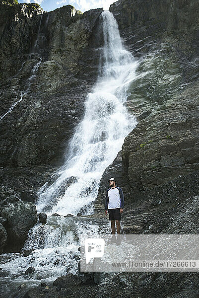 Russia  Karachay-Cherkessia  Arkhyz  Man standing near Sofiyskiye Vodopady waterfall in Caucasus Mountains