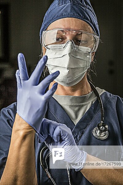 Besorgte Ärztin oder Krankenschwester  die Gesichtsschutz und Operationshandschuhe anzieht