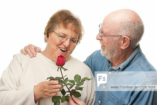 Glückliches älteres Paar mit roter Rose vor einem weißen Hintergrund