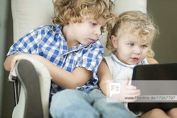 Adorable young brother and sister using their computer laptop together