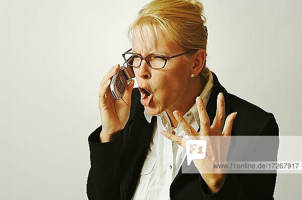 Geschäftsfrau drückt ihre Wut aus  während sie mit ihrem Handy telefoniert