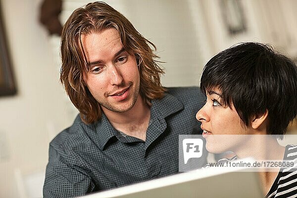 Glücklicher junger kaukasischer Mann und multiethnische Frau verwenden den Laptop-Computer zusammen