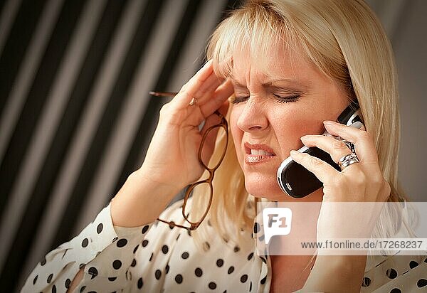 Blonde Frau auf ihrem Handy mit gestressten Blick auf ihr Gesicht