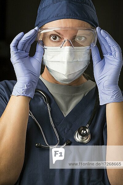 Besorgte Ärztin oder Krankenschwester  die eine Gesichtsschutzkleidung anlegt