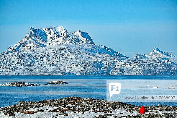 Mensch mit roter Jacke vor Fjord und Bergen mit Schnee  Abendstimmung  Nuuk  Dänmark  Grönland  Nordamerika