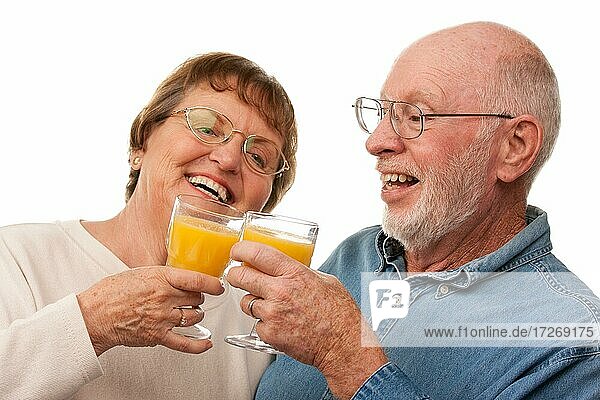 Glückliches älteres Paar mit Gläsern von Orangensaft vor einem weißen Hintergrund