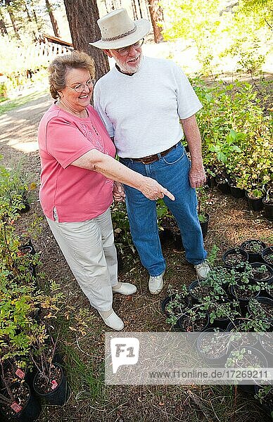 Attraktives Seniorenpaar mit Blick auf Topfpflanzen in der Gärtnerei