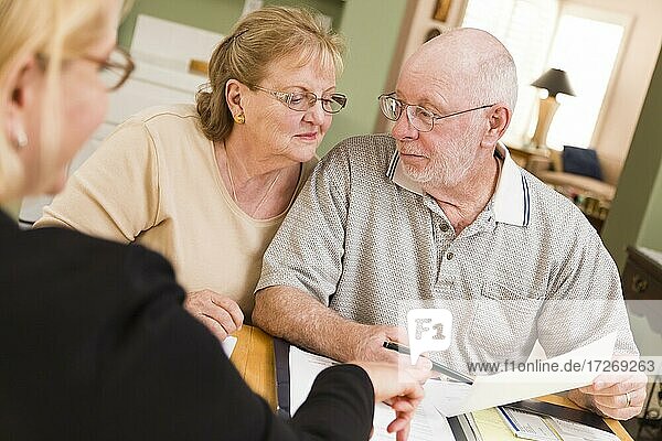 Senior adult couple going over papers in their home with agent