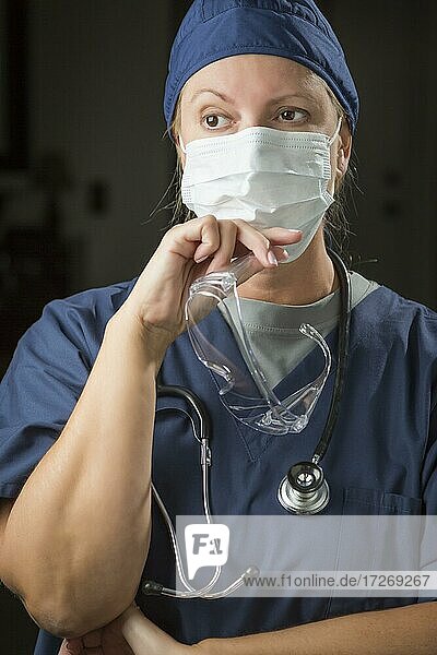 Besorgte Ärztin oder Krankenschwester mit Mundnasenschutz und Schutzbrille