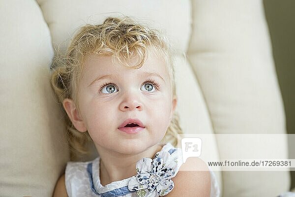Adorable blonde Haare und blaue Augen kleines Mädchen sitzt im Stuhl