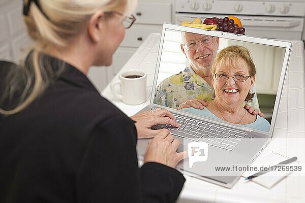 Frau in der Küche mit Laptop  Online-Chat mit älterem Paar oder Eltern auf dem Bildschirm
