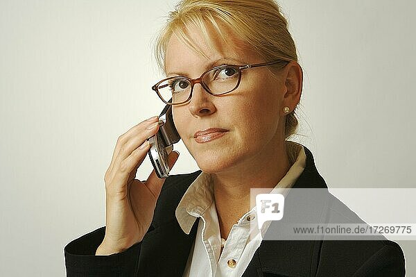 Geschäftsfrau mit Mobiltelefon auf einem grauen Hintergrund