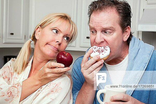 Paar in der Küche essen Donut und Kaffee oder gesunde Früchte