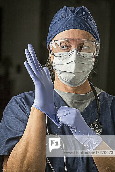 Besorgte Ärztin oder Krankenschwester  die Gesichtsschutz und Operationshandschuhe anzieht