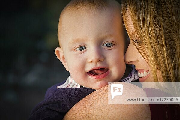 Adorable roten Kopf Säugling Junge Porträt mit seiner Mutter im Freien in dramatischen Beleuchtung