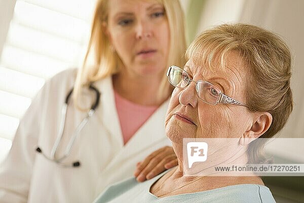 Melancholy senior adult woman being consoled by female doctor or nurse