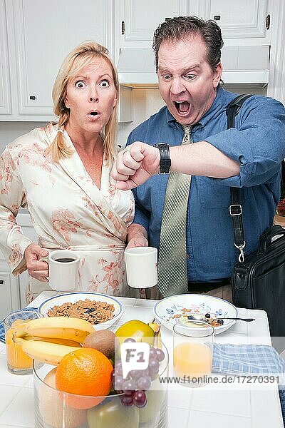 Spät zur Arbeit gestresstes Paar  das die Zeit in der Küche überprüft