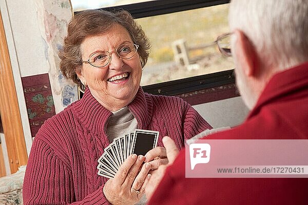 Glückliches älteres erwachsenes Paar spielt Karten in ihrem Wohnmobil