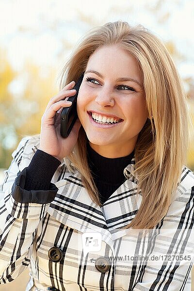 Hübsche junge blonde Frau auf ihr Handy draußen auf Herbst Tag