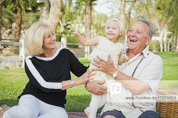 Zärtliche Enkelin und Großeltern spielen draußen im Park