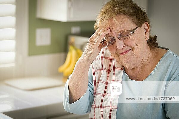 Traurige weinende ältere Frau an der Küchenspüle im Haus