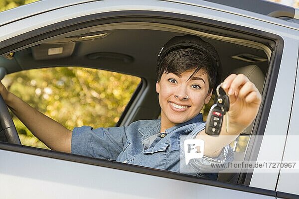 Glücklich lächelnde gemischtrassige Frau im Auto  die einen Schlüsselbund hält