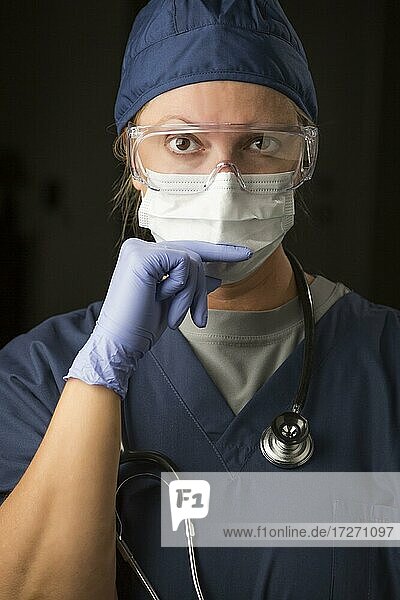 Besorgte Ärztin oder Krankenschwester mit Gesichtsschutz und OP-Handschuhen