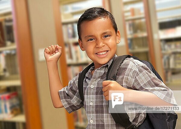 Happy hispanic student boy with backpack in the library