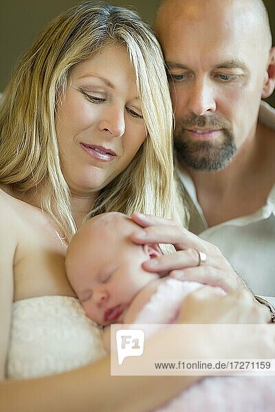 Schönes junges Paar hält ihr neugeborenes schlafendes Baby Mädchen im Inneren