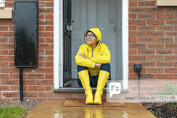 Frau schaut weg  während sie in der Regenzeit zu Hause auf der Tür sitzt