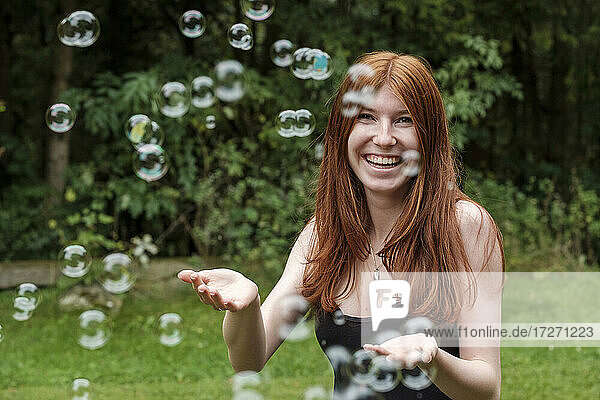 Glückliche Frau spielt mit Seifenblasen im Hinterhof