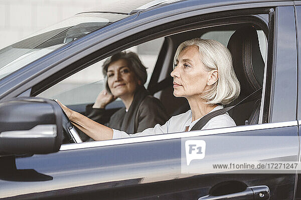 Kollege sitzt mit Geschäftsfrau beim Autofahren in der Stadt