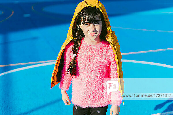 Cute girl wearing padded jacket while standing on sports court