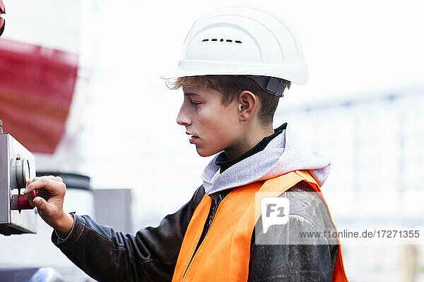 Male teenage trainee using machinery at construction site