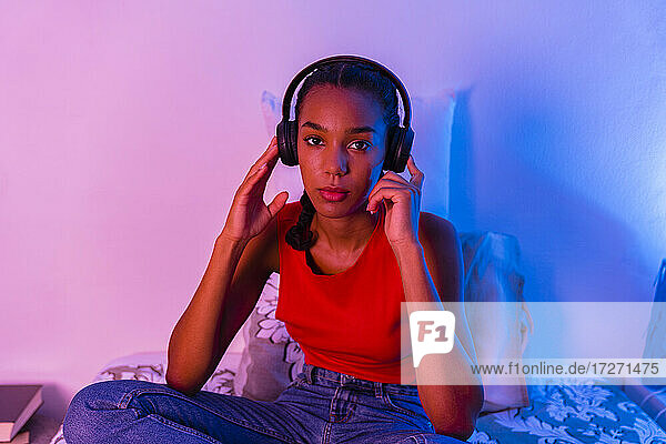 Junges Mädchen hört Musik  während sie zu Hause im Schlafzimmer sitzt