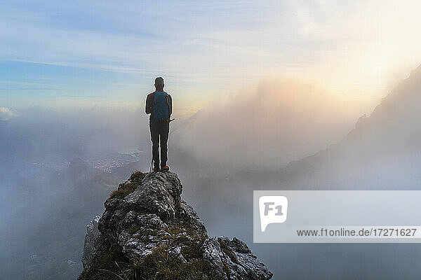 Pensive male hiker standing on mountain peak during sunrise at Bergamasque Alps  Italy